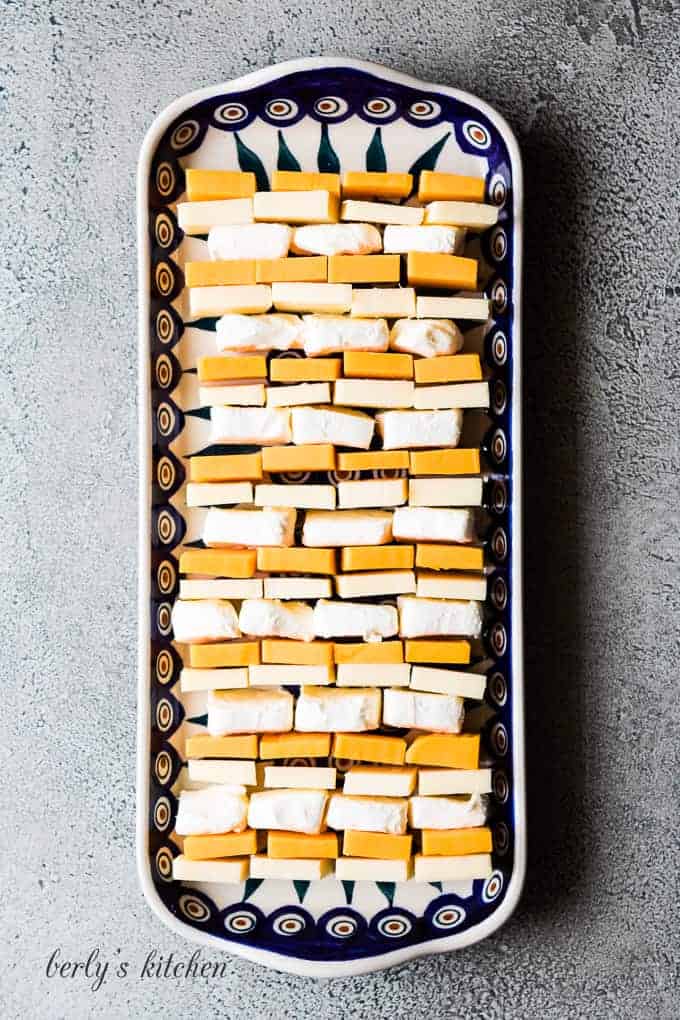 The cheese squares arranged on a platter with tall rim.