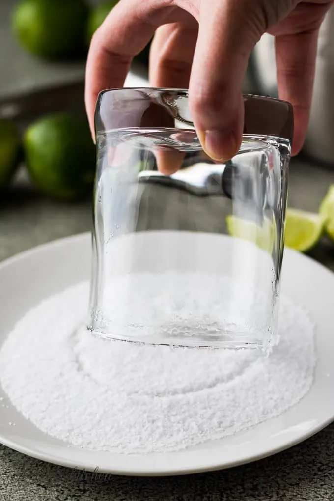 The rim of the cocktail glass being dipped into salt.