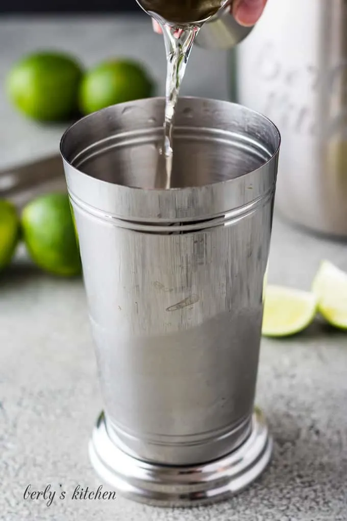 A shot of tequila being added to a cocktail shaker.
