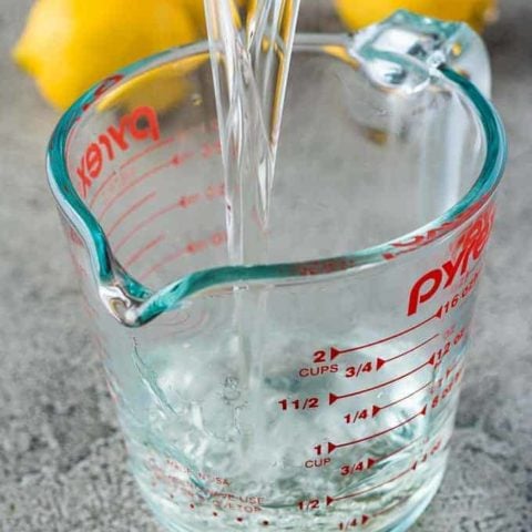 Simple Syrup For Drinks The finished syrup mixture pouring into a glass measuring cup.