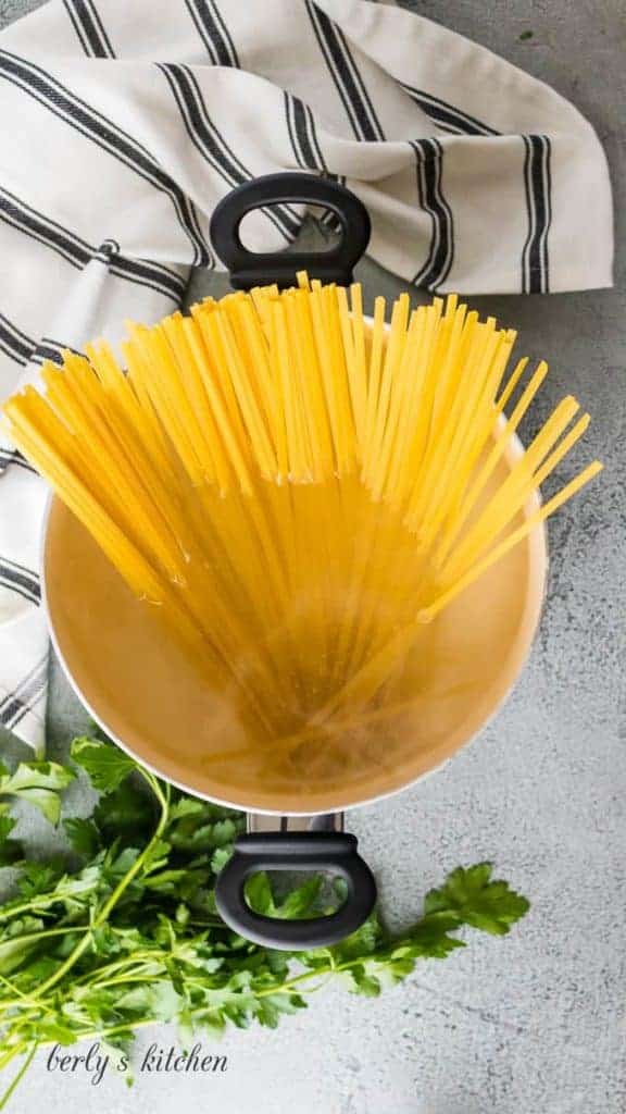 Fettuccine noodles cooking in a pan.