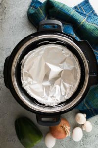 The uncooked frittata covered with aluminum foil in a pressure cooker.