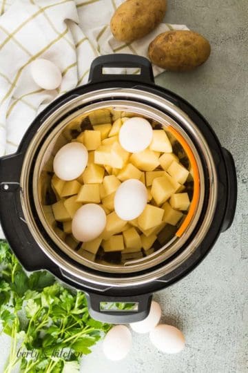 Ariel view of a pressure cooker with a basket of potatoes and 4 eggs on top.