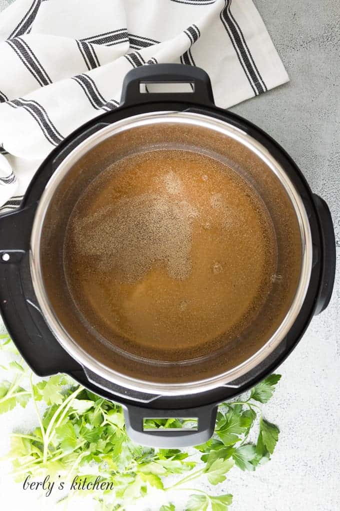 Vegetable broth and spices in the pressure cooker liner.