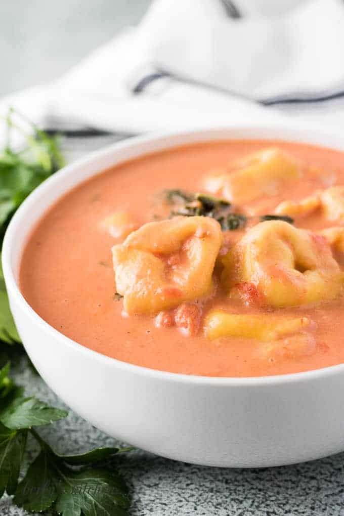 The finished creamy tortellini soup garnished with kale.