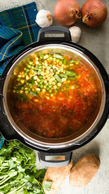 Frozen mixed vegetables being added to the hot soup.