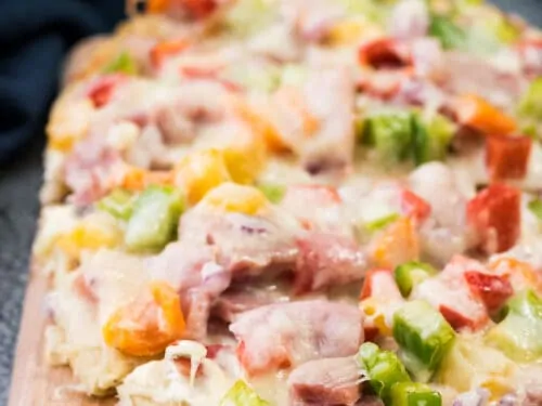 The ham flatbread on a wooden cutting board.
