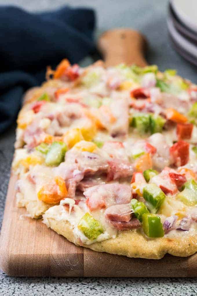 The ham flatbread on a wooden cutting board.