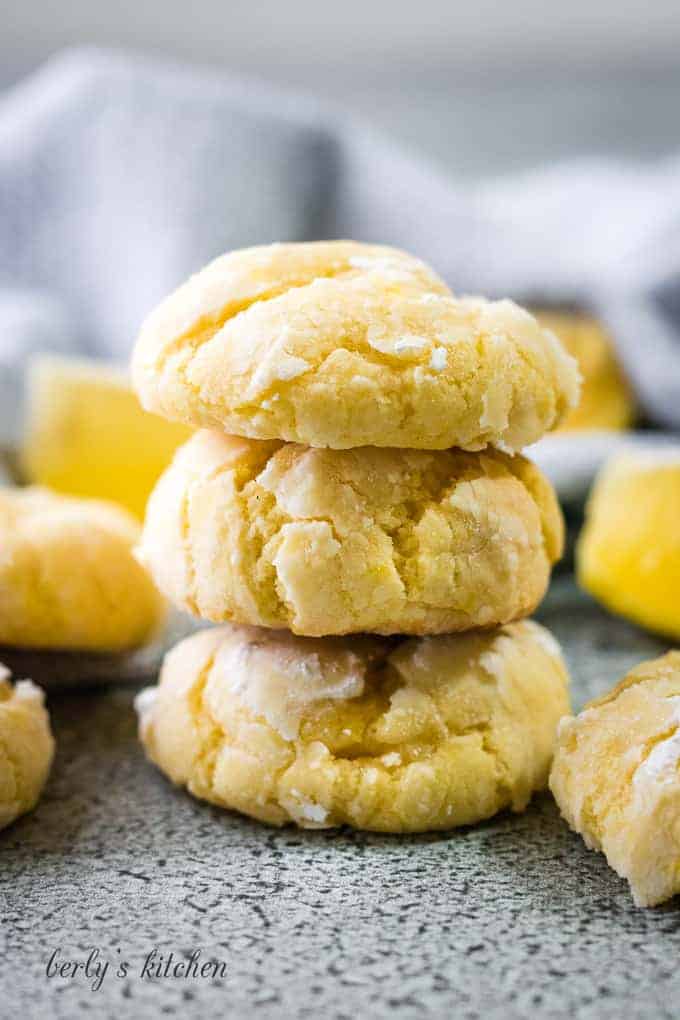 Lemon crinkle cookies surrounded by fresh lemon wedges.