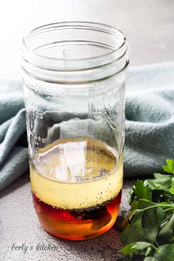 Vinegar, oil, and poppy seeds in a mason jar.