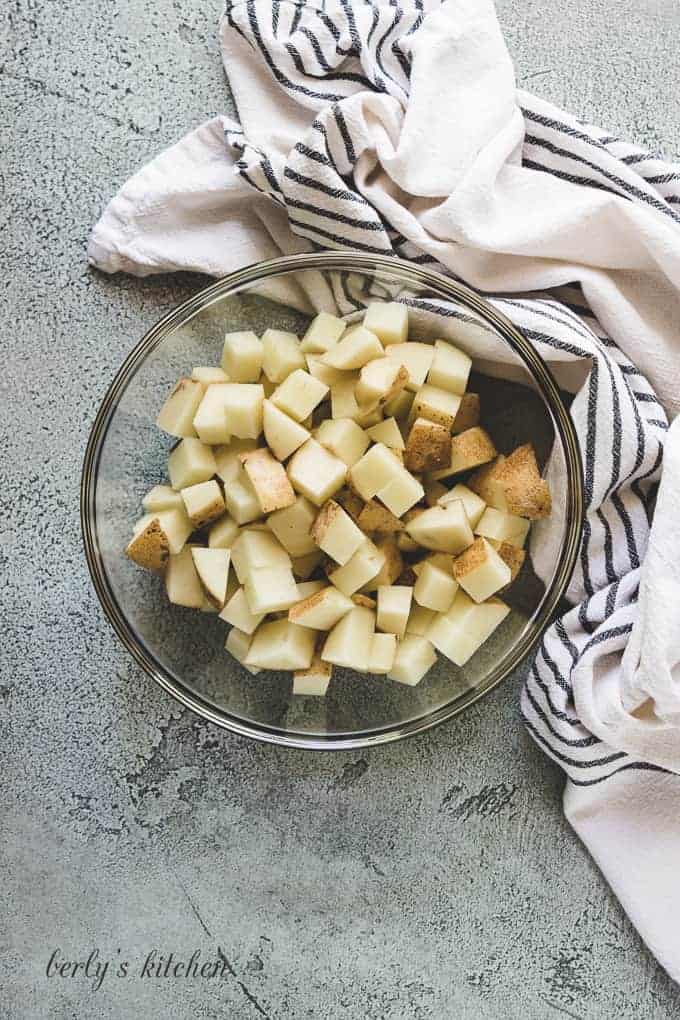 Cubed potatoes in a large glass mixing bowl.