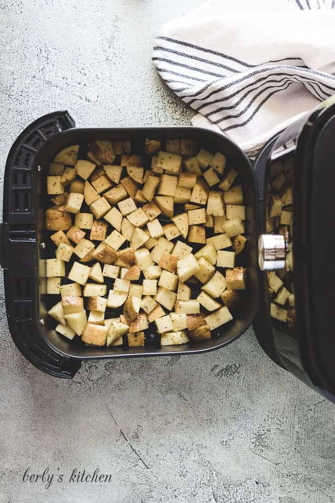 The potatoes have been transferred to the air fryer basket.