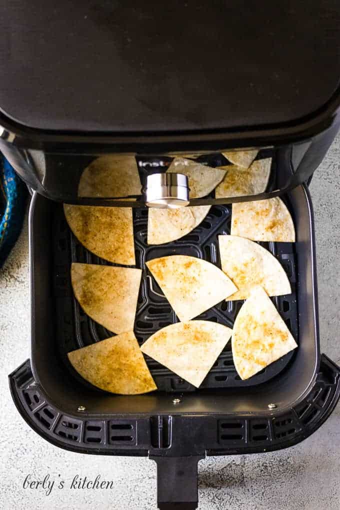 Corn tortilla chips cooking in an air fryer.