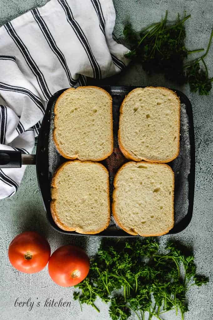 Four slices of sourdough cooking in skillet.