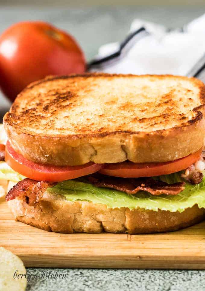 The completed blt sandwich surrounded by potato chips.