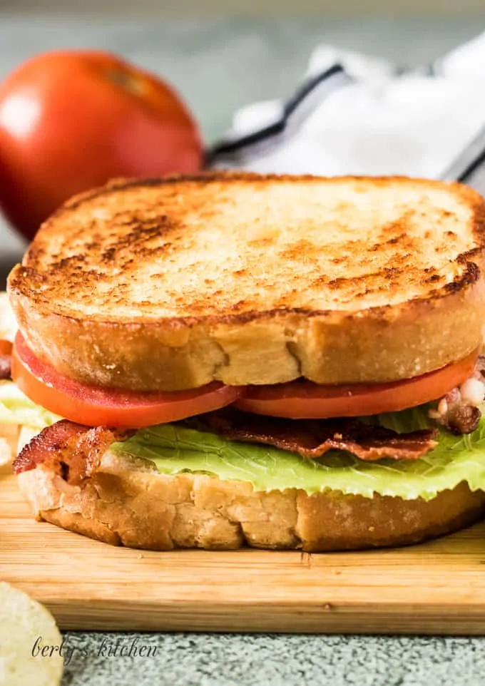 The completed blt sandwich surrounded by potato chips.