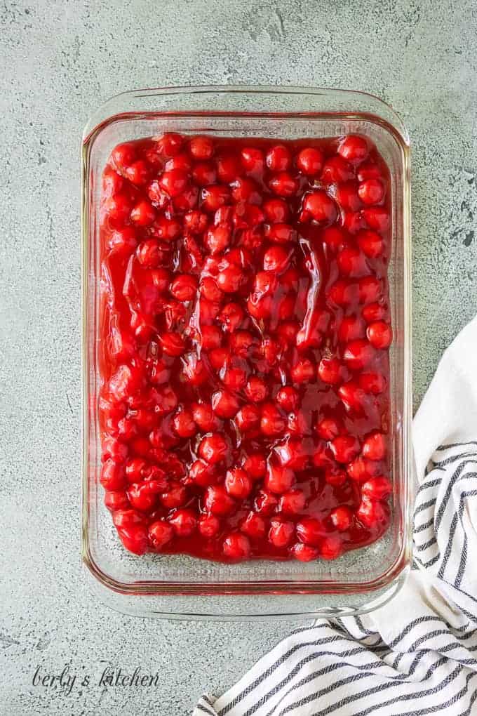 The cherry pie filling has been poured into the baking dish.