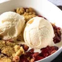 A close-up of the cherry dump cake topped with 2 scoops of vanilla ice cream.