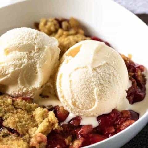 Cherry Dump Cake Recipe A close-up of the cherry dump cake topped with 2 scoops of vanilla ice cream.