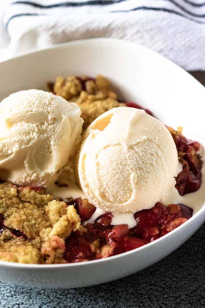 A close-up of the cherry dump cake topped with 2 scoops of vanilla ice cream.