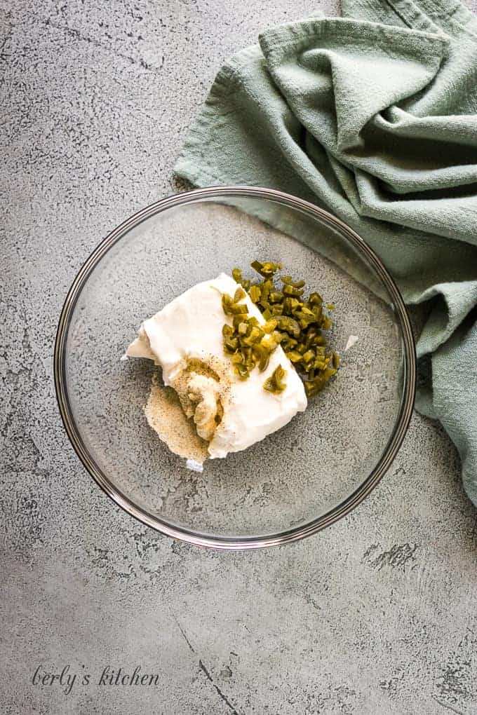 Cream cheese, spices, and jalapenos in a mixing bowl.