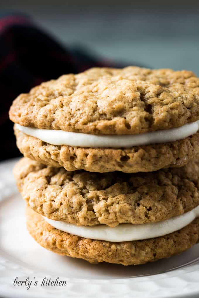 Two cookie sandwiches stacked on a white plate.