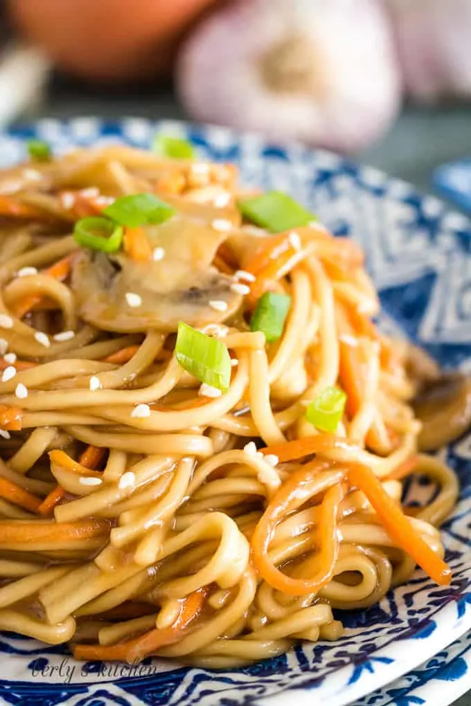 Vegetable lo mein served on a plate and topped with sliced green onions.