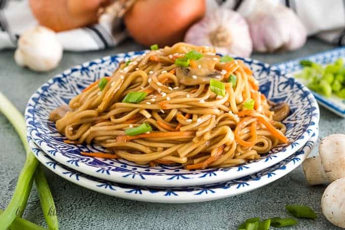 A blue and white plate with a serving of vegetable lo mein.