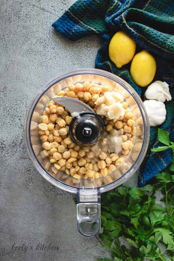 Chickpeas, tahini, and other ingredients in a food processor.