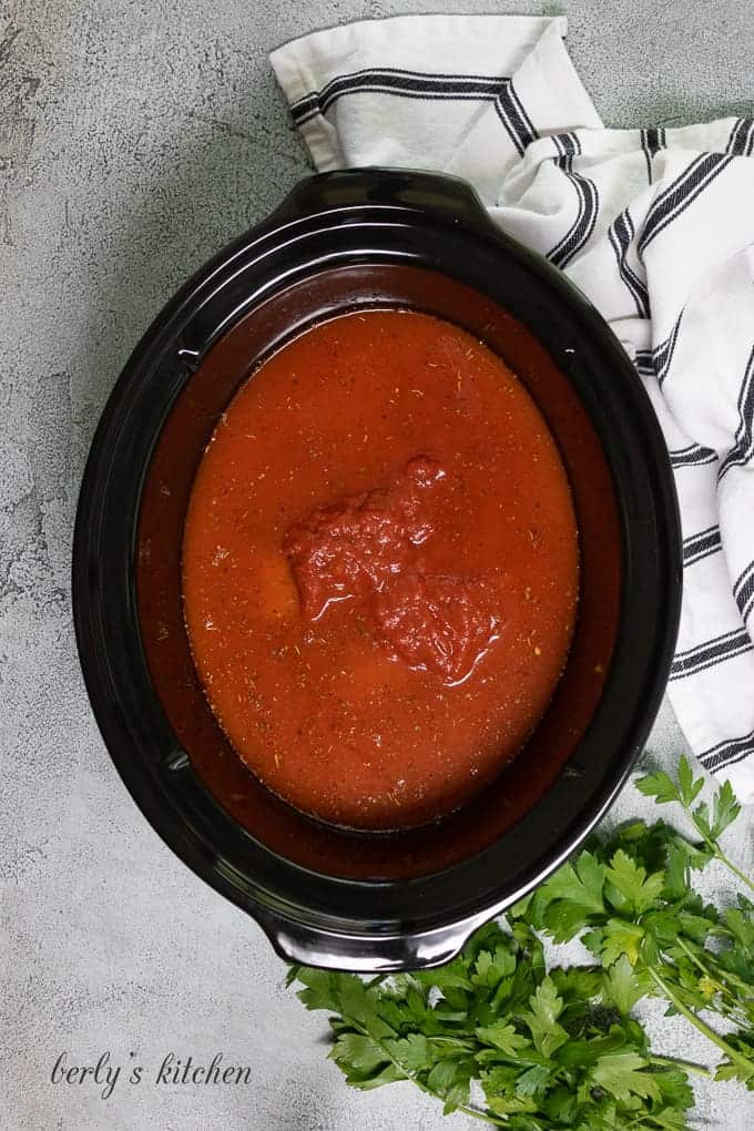Chicken, sauce, and water in the slow cooker.