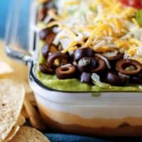 7 layer dip in a dish next to tortilla chips.