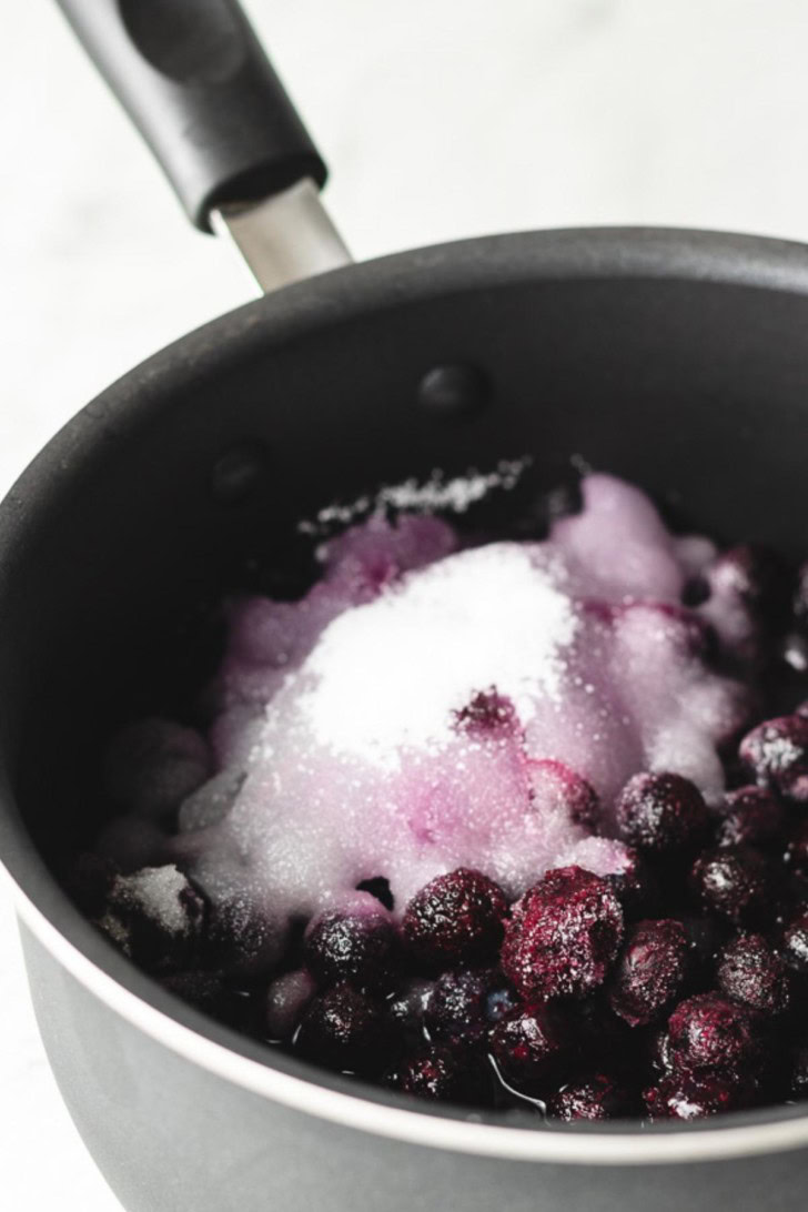 A medium saucepan filled with water, blueberries, and sugar.