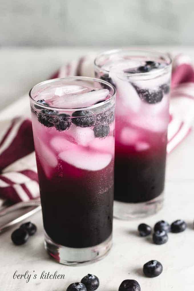 The soda made with blueberry syrup served in glasses.