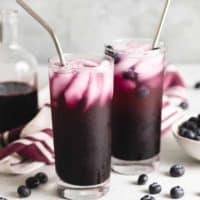 The blueberry soda served with straws and ice.