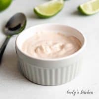 The creamy chipotle sauce served in a small ramekin with lime wedges.