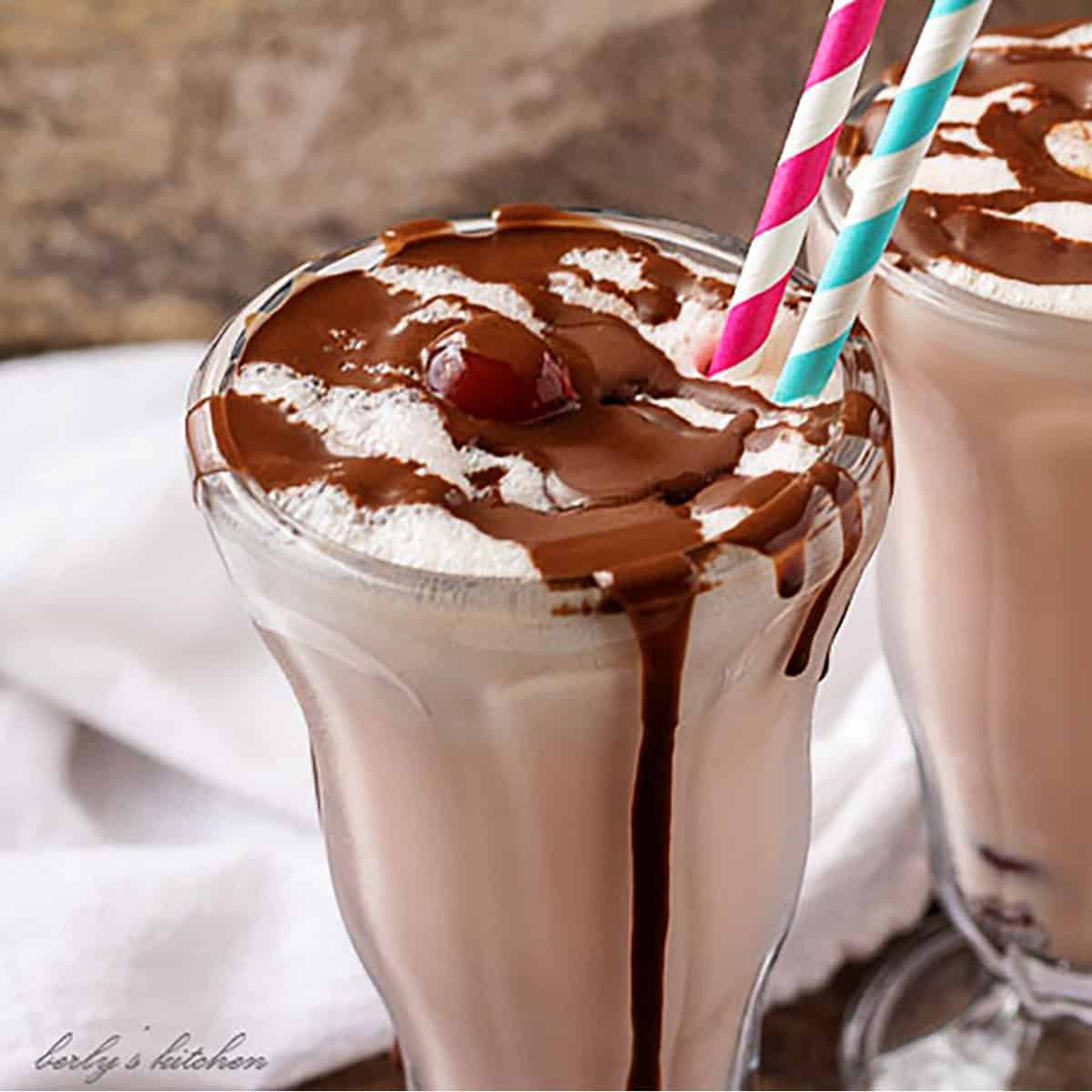 Two glasses of cherry milkshake covered in melted chocolate.