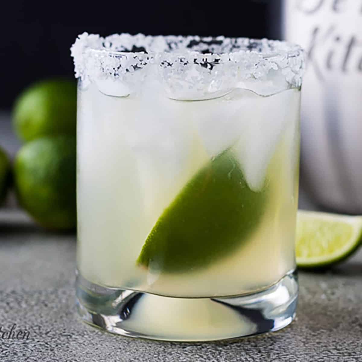 Margarita with a lime in a salt-rimmed cocktail glass.