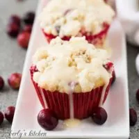 Cranberry orange muffins on a platter with fresh cranberries.