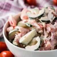 Bowl of chopped cucumbers and tomatoes tossed in ranch dressing.