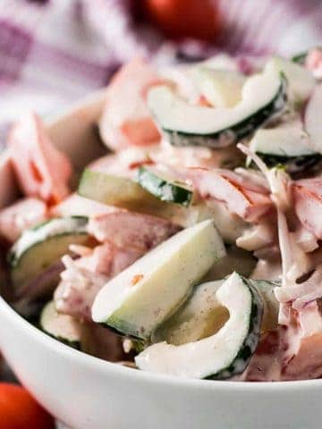 Bowl of chopped cucumbers and tomatoes tossed in ranch dressing.