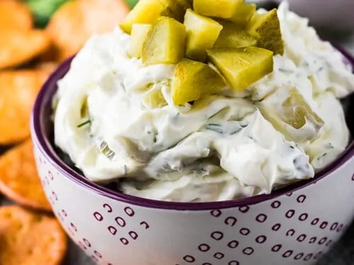 Dill pickle dip topped with chopped pickles in a small bowl.