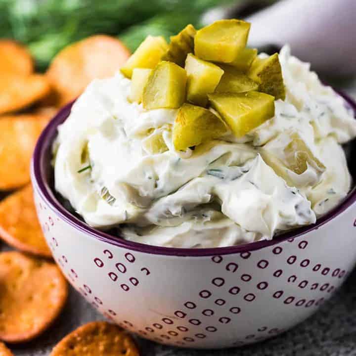 Dill pickle dip topped with chopped pickles in a small bowl.