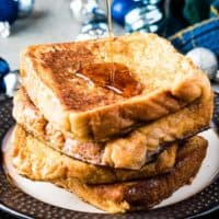 Stack of eggnog French toast being drizzled with syrup.