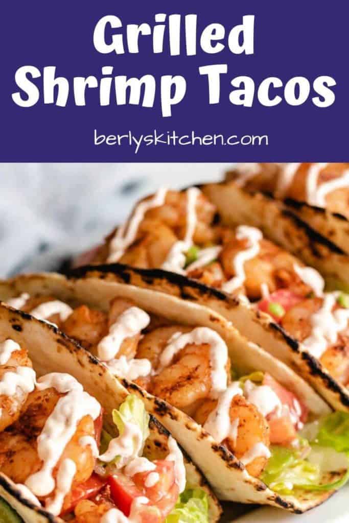 A close-up of three shrimp tacos on a platter.