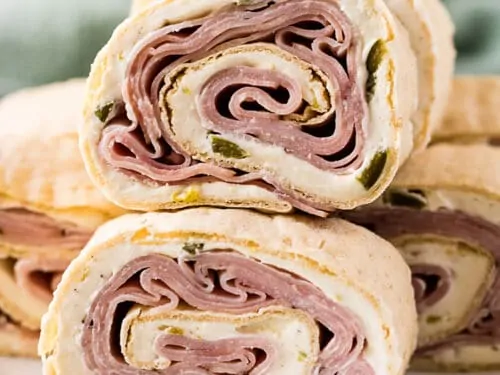 Ham and cheese pinwheels stacked on a plate.