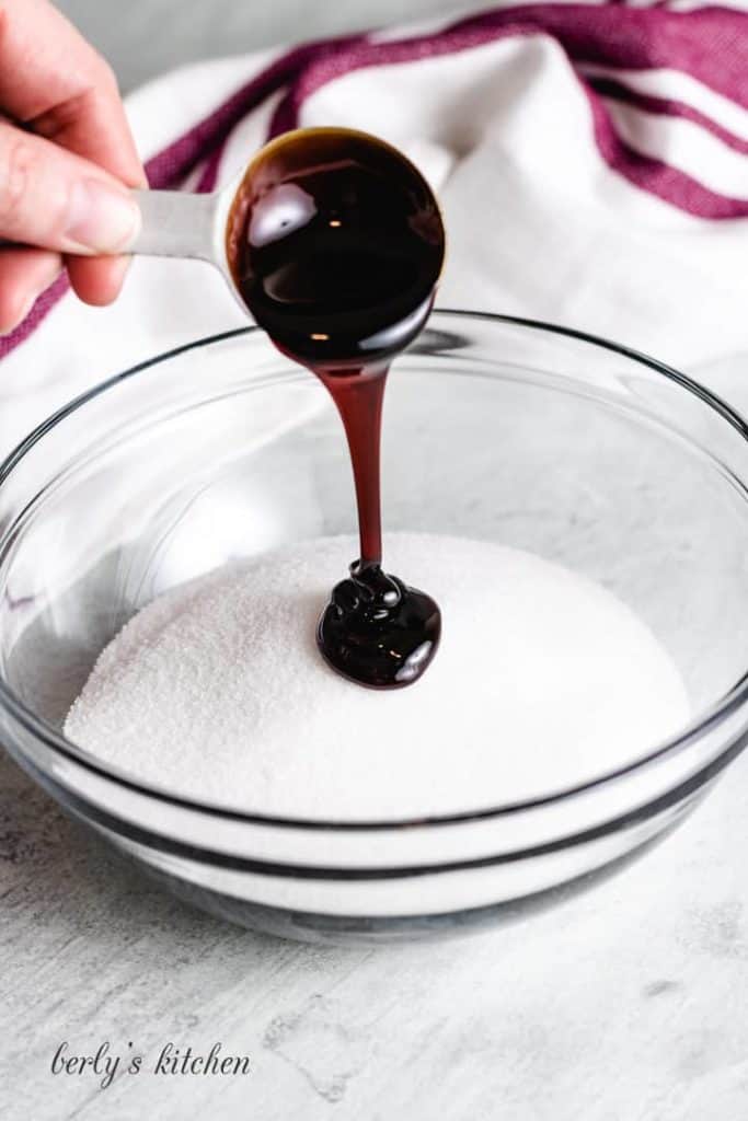 A tablespoon of molasses added to a bowl of sugar.