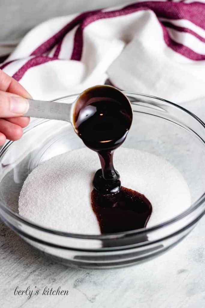 Two tablespoons of molasses added to sugar in a bowl.