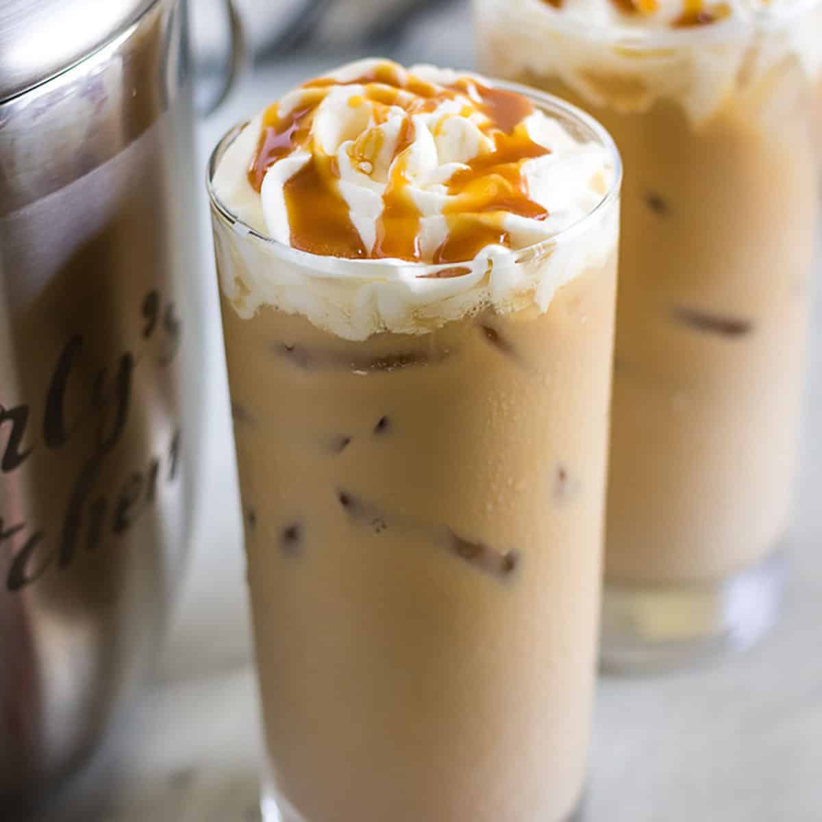 Two glasses of iced coffee with whipped cream and caramel sauce.