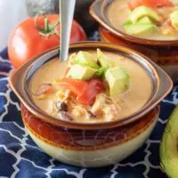 Bowl of Instant Pot Chicken Taco Soup with tomatoes and fresh avocado.