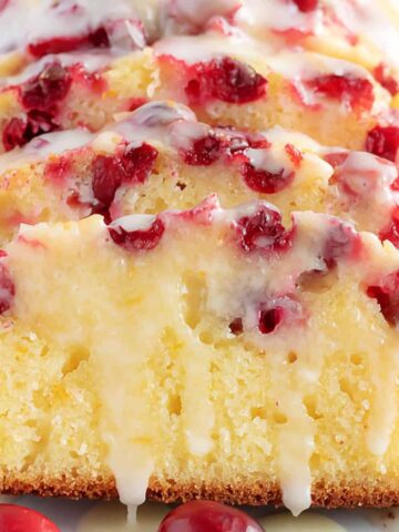 Sliced orange cranberry bread with glaze.